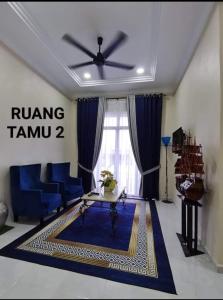 a living room with blue furniture and a ceiling fan at FIYA ViLA HOMESTAY in Ketereh