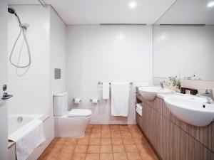 a bathroom with two sinks and a toilet and a tub at Desert Gardens Hotel in Ayers Rock