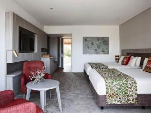 a hotel room with two beds and a table and chairs at Desert Gardens Hotel in Ayers Rock