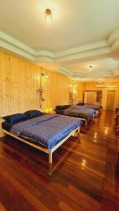 eine Reihe von Betten in einem Zimmer mit Holzböden in der Unterkunft Khunkhao Maenamchan Homestay ขุนเขา แม่น้ำจัน โฮมสเตย์ in Chiang Rai