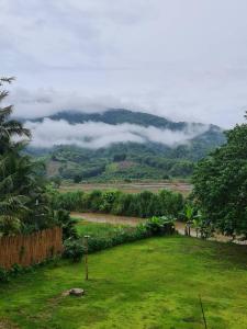 a green field with a view of a mountain at Khunkhao Maenamchan Homestay ขุนเขา แม่น้ำจัน โฮมสเตย์ in Chiang Rai