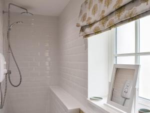 a white bathroom with a shower and a window at The Old Workshop in Keswick