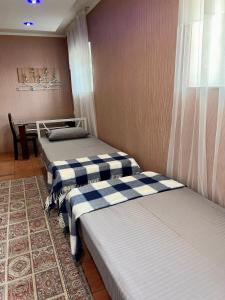 two beds in a room with a table at InJoy in Shymkent