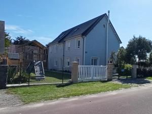 niebieski dom z białym płotem obok ulicy w obiekcie Gîte La Mer, 50m de la mer w mieście Saint-Germain-sur-Ay