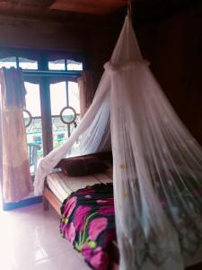 a bed with a canopy in a room with a window at WATUGANA BUNGALOW KELIMUTU in Kelimutu