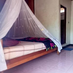 a bed with a mosquito net in a room at WATUGANA BUNGALOW KELIMUTU in Kelimutu