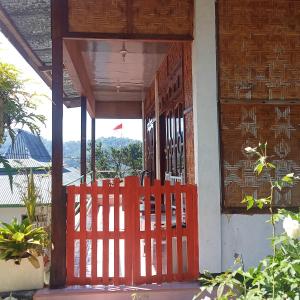 una entrada a una casa con una puerta roja en WATUGANA BUNGALOW KELIMUTU en Kelimutu