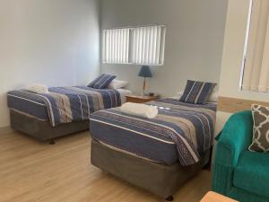 a room with two beds and a chair in it at Mandurah Ocean Marina Chalets in Mandurah