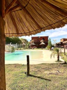 a resort with a swimming pool and a large umbrella at CABAÑAS COSTA RIBERA in Timbues