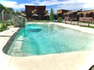 a swimming pool with blue water in a yard at CABAÑAS COSTA RIBERA in Timbues