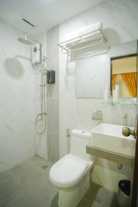 a white bathroom with a toilet and a sink at Ragazzi Resort Hotel in Naga