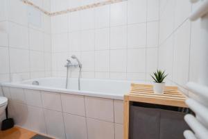 a white bathroom with a tub and a plant on a table at Blue Chili 02 - MD Zentral City Carré Wlan Netflix in Magdeburg