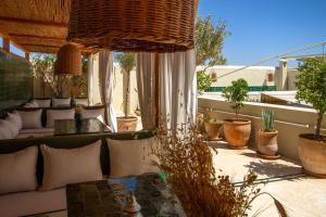 eine Terrasse mit einem Sofa, einem Tisch und Pflanzen in der Unterkunft Riad Bab 54 in Marrakesch