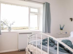 a white bed in a bedroom with a window at Cerrig in Holyhead