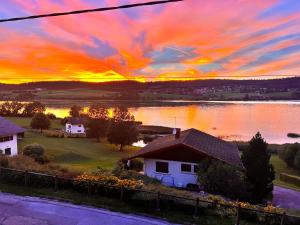 Chalet Charmant rénové au bord du Lac St Point في Montperreux: إطلالة الغروب على المنزل والبحيرة