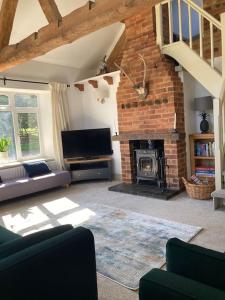 a living room with a fireplace and a brick wall at Spacious Cottage in Idyllic Spot in Fenny Compton