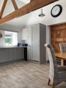 a kitchen with a table and a clock on the wall at Spacious Cottage in Idyllic Spot in Fenny Compton