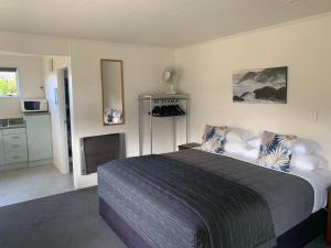 a bedroom with a large bed and a kitchen at Amber Court Motel in Te Anau