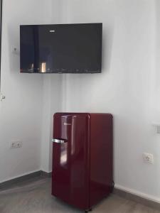 a red refrigerator in a room with a tv on the wall at Seaside Serenade 1, suite in Ermoupoli