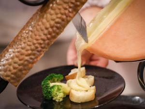 uma pessoa está a derramar molho num prato com brócolos em Sasai Hotel em Otofuke