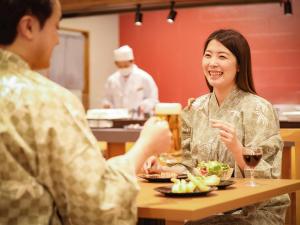 a man and woman sitting at a table with a glass of beer at Sasai Hotel in Otofuke