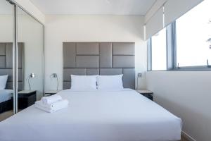 een slaapkamer met een groot wit bed en een spiegel bij Comfort Two bedroom Apartment with Free parking In Valley in Brisbane