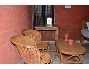 three wicker chairs and a table and a table and a tableablish at Rekha & Kamla Homestay, Orchha 