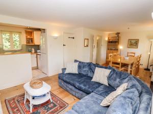a living room with a blue couch and a table at Kingfisher House in Somerford Keynes