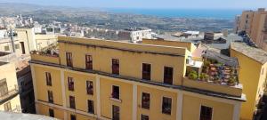 un bâtiment jaune avec des fleurs sur ses balcons dans l'établissement terrazze di montelusa, à Agrigente