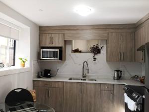 a kitchen with wooden cabinets and a sink and a microwave at Lucy's Place - Two Bedroom Suite in Vancouver