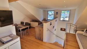 ein Wohnzimmer mit einer Treppe und eine Küche mit einem Tisch in der Unterkunft The Apartment - Alpentherme inklusive in Bad Hofgastein