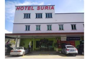 JQ Suria Hotel في Lahat: فندق يقف امامه سيارتين