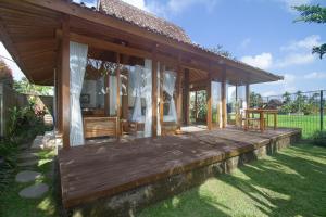 une maison avec une terrasse en bois dans la pelouse dans l'établissement Kabinawa Ubud Villas by Pramana Villas, à Ubud