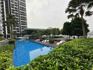 a swimming pool with white lounge chairs and buildings at Educity Legoland Eco Botanic Homestay in Johor Bahru