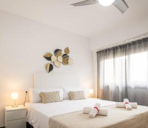 a white bedroom with two beds and a window at Macflats Ciudad de las Ciencias in Valencia