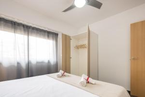 a bedroom with a white bed with two towels on it at Macflats Ciudad de las Ciencias in Valencia