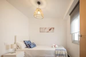 a white bedroom with a bed and a pendant light at Macflats Ciudad de las Ciencias in Valencia