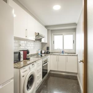 a kitchen with white cabinets and a washer and dryer at Macflats Ciudad de las Ciencias in Valencia