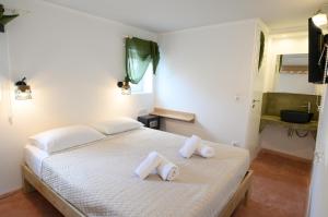 a bedroom with a white bed with towels on it at Lakki Village in Aegiali