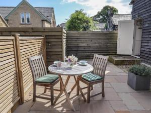 a table and chairs on a patio with a fence at Bay Tree Studio in Alnmouth