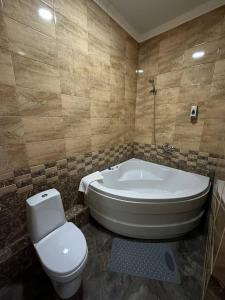 uma casa de banho com um WC e uma banheira em Бутик-отель Мажор em Aqtöbe