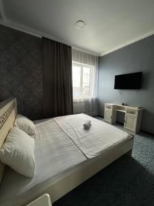 a hotel room with a bed and a television at Бутик-отель Мажор in Aktobe