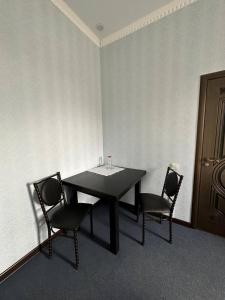a black table and two chairs in a room at Бутик-отель Мажор in Aktobe