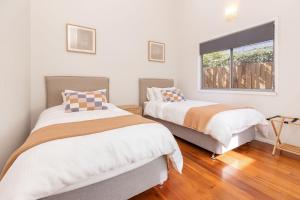 two beds in a room with a window at Lazuli in Blueys Beach