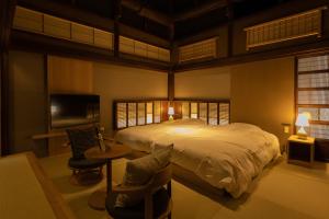 Classic ＆ modern SELF-STYLED HOTEL 番場おおそね في تشيتشيبو: غرفة نوم بسرير وطاولة وكراسي