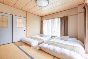 - 2 lits dans une chambre avec une grande fenêtre dans l'établissement Azami Ann Maisonette, à Shirahama