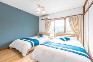 2 łóżka w sypialni z niebieskimi ścianami i oknem w obiekcie Azami Ann Maisonette w mieście Shirahama