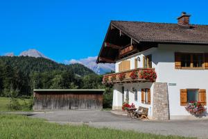 a white building with flowers on the windows and a balcony at Maurerlehen in Berchtesgaden
