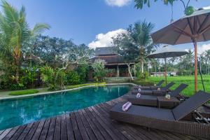 - une piscine avec des chaises longues et un parasol dans l'établissement Kabinawa Ubud Villas by Pramana Villas, à Ubud