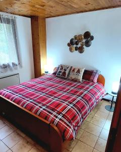 a bedroom with a bed with a red plaid blanket at Il Belvedere in Nevegal